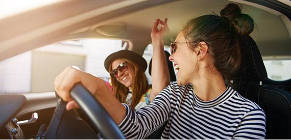 Two friends dancing in a car.